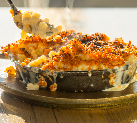 Baked macaroni and cheese with a crispy golden crust in a black dish.