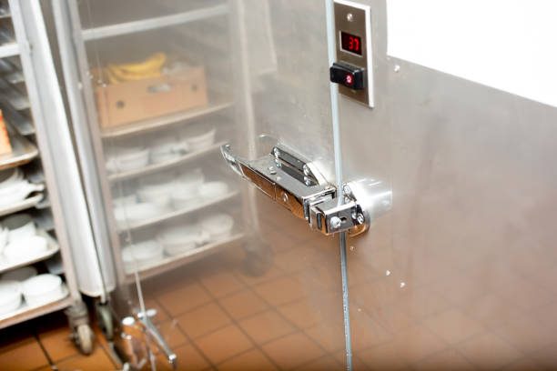 Close-up of a stainless steel door latch with a digital temperature display in a kitchen.