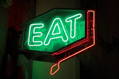 Neon sign displaying the word "EAT" in green with a red outline.