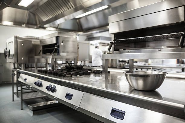 Modern commercial kitchen with stainless steel appliances and a large preparation table.
