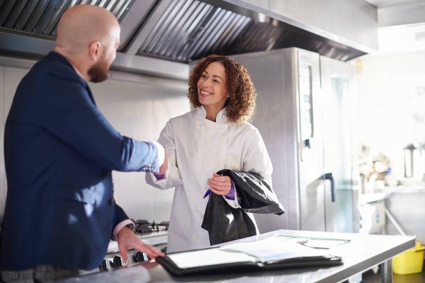 A man and woman shake hands in a modern kitchen setting.