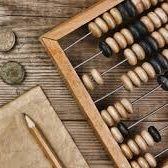 Wooden abacus with black and white beads, coins, and a pencil on a wooden surface.