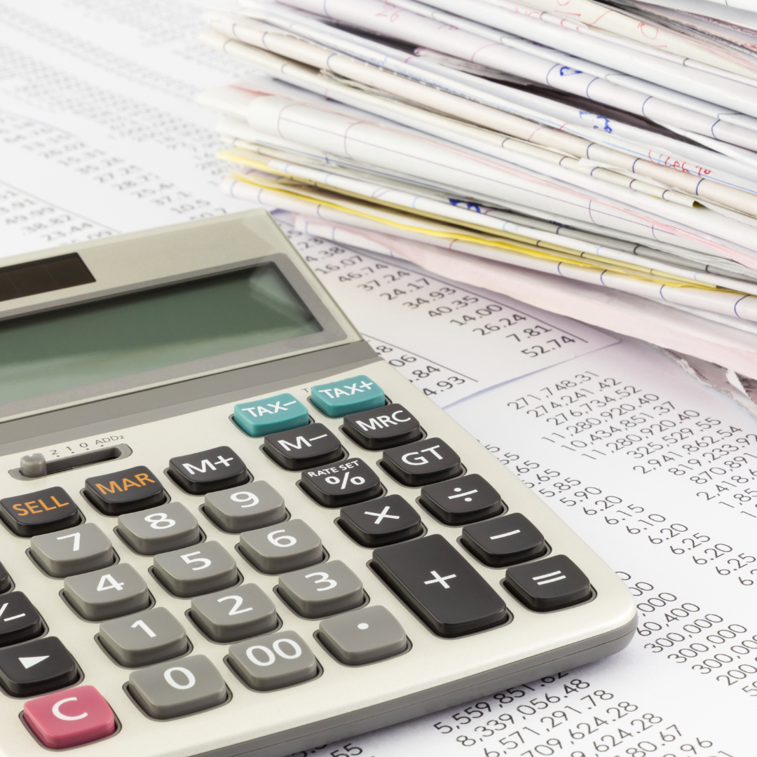 Calculator on a table with papers and printed numbers.